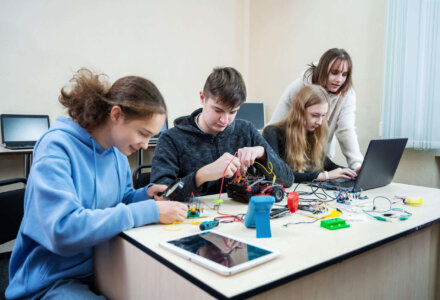 Vier Jugendliche arbeiten an einem Technikprojekt mit Kabeln, Laptop und Bauteilen