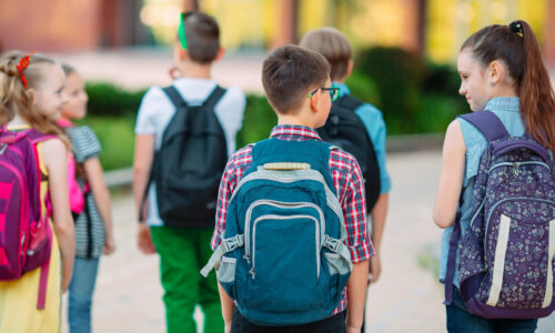 Gruppe von Schulkindern mit Rucksäcken auf dem Weg zur Schule
