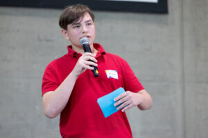 Ein Schüler stellt sein Forschungsprojekt vor Publikum vor.