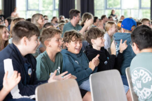 Schüler:innen applaudieren und reagieren begeistert auf eine Projektpräsentation.
